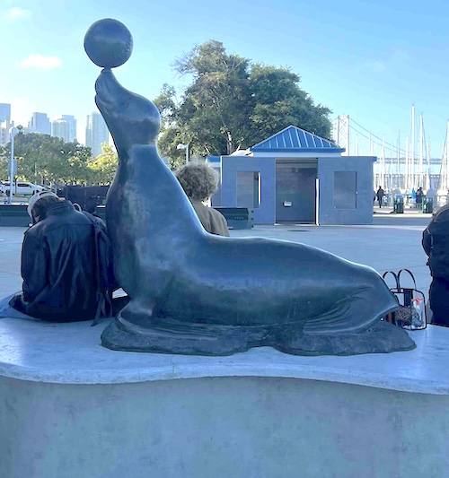 A statue of a seal balancing a ball on its nose.