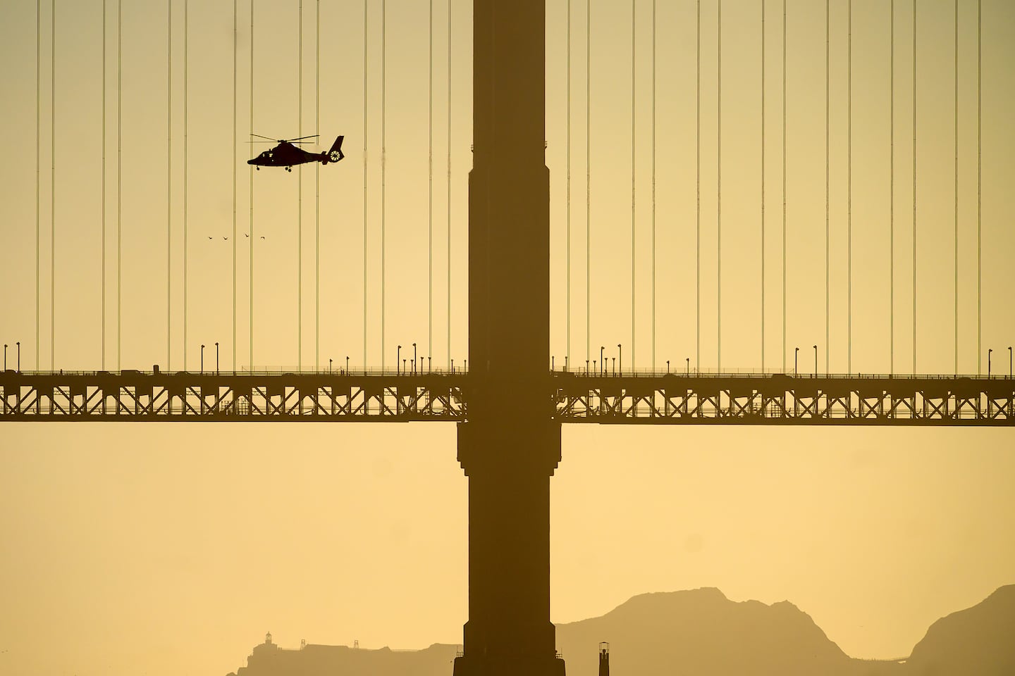 A helicopter flies past the Golden Gate Bridge while searching for missing victims after a boat accident near Alcatraz Island off San Francisco.