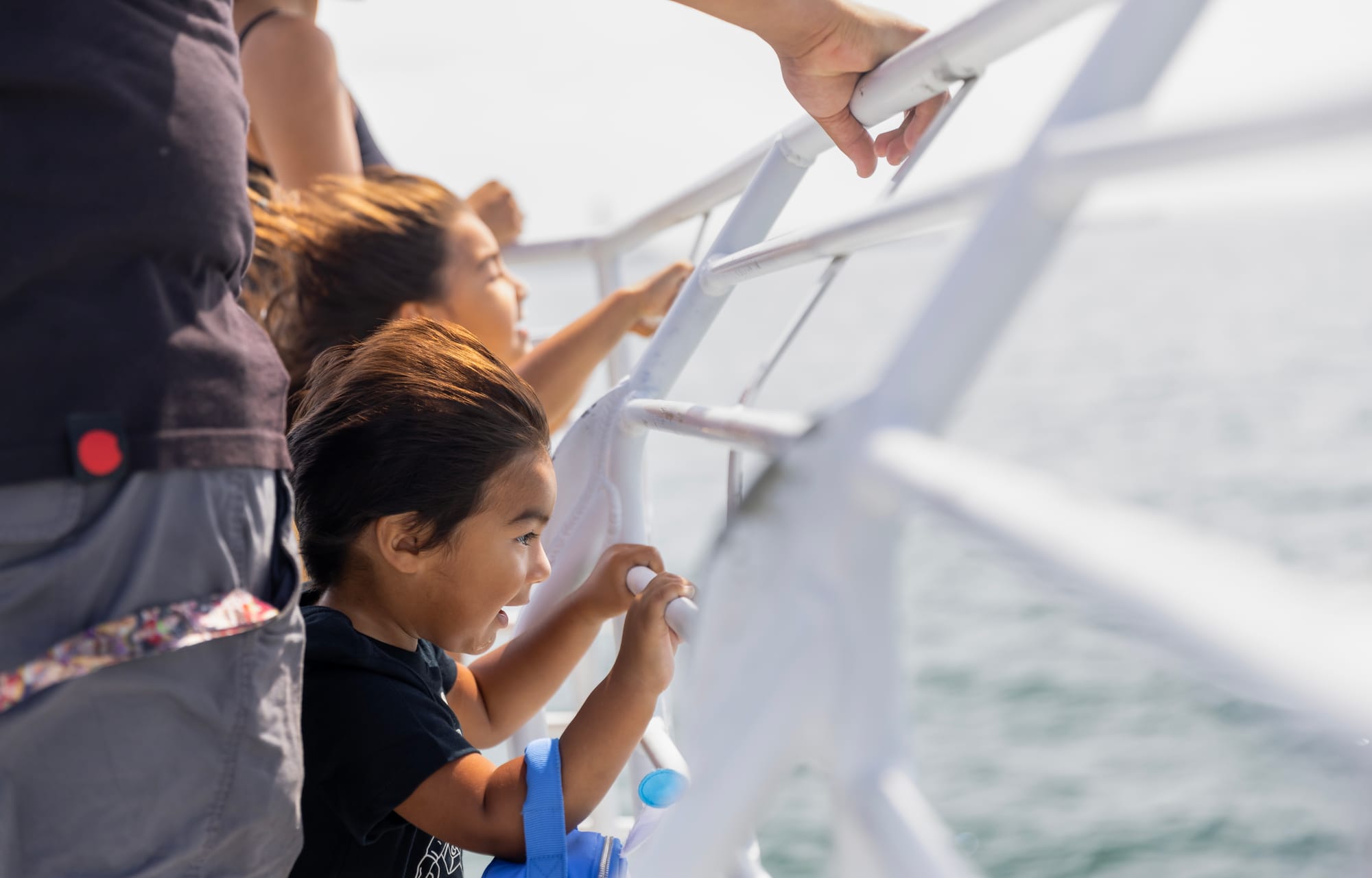 Small kids on a boat look out on the ocean.