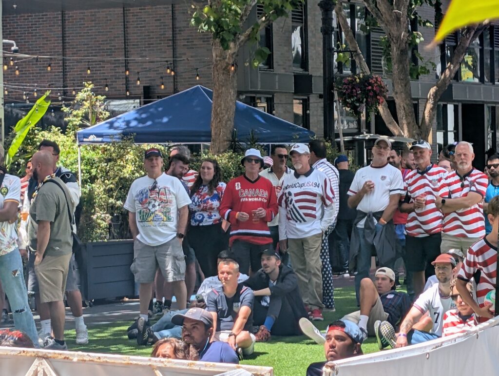 People watching a soccer match on a large screen.