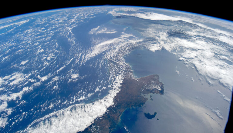 the curved edge of a blue Earth with white clouds seen from space