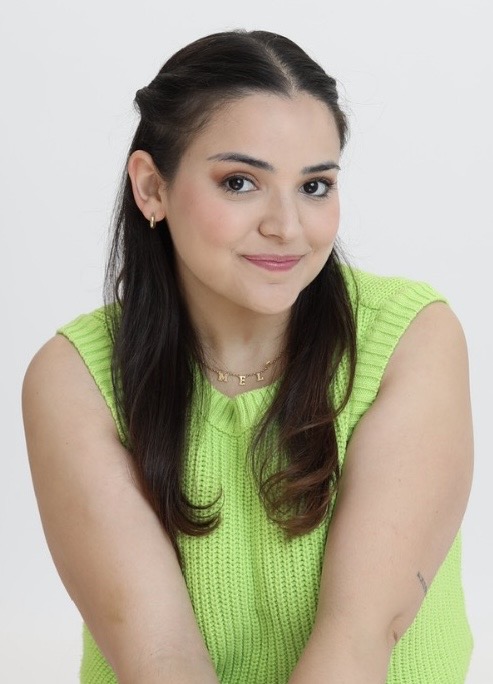 Young woman with dark hair in a green sleeveless top, smiling, against a white background.