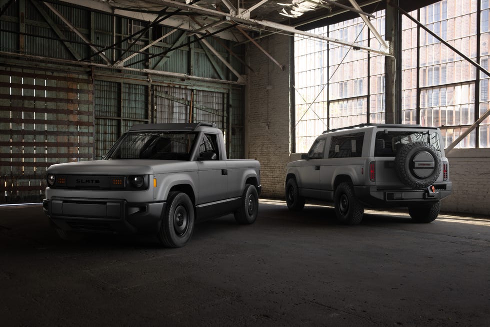 Two modern vehicles, a pickup truck and an SUV, parked in an industrial setting with large windows and exposed beams.