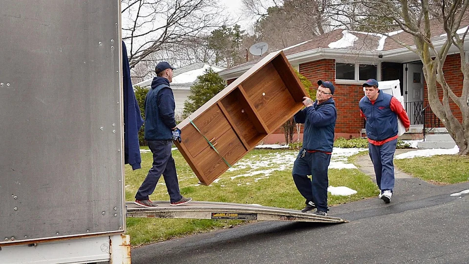 workers carry furniture into truck