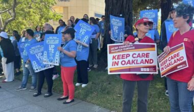 Staff and family members of patients at UCSF Benioff Children's Hospital Oakland in Oakland, Calif., hold signs during a rally on Thursday, July 9, 2026. Rally participants protested the relocation of specialized care clinics to the hospital's San Francisco campus. Photo by Kayla Chan/Bay City News.