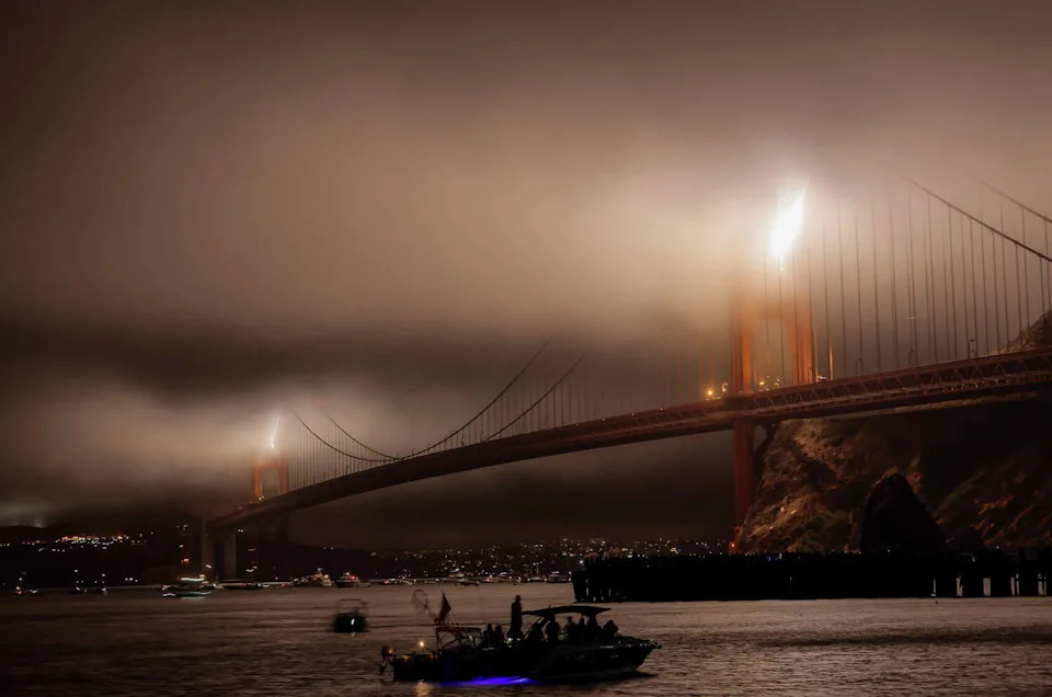 Fourth of July fireworks peek through the fog over the Golden Gate Bridge as San Francisco celebrates the nation's 250th birthday. (Carlos Avila Gonzalez/S.F. Chronicle)