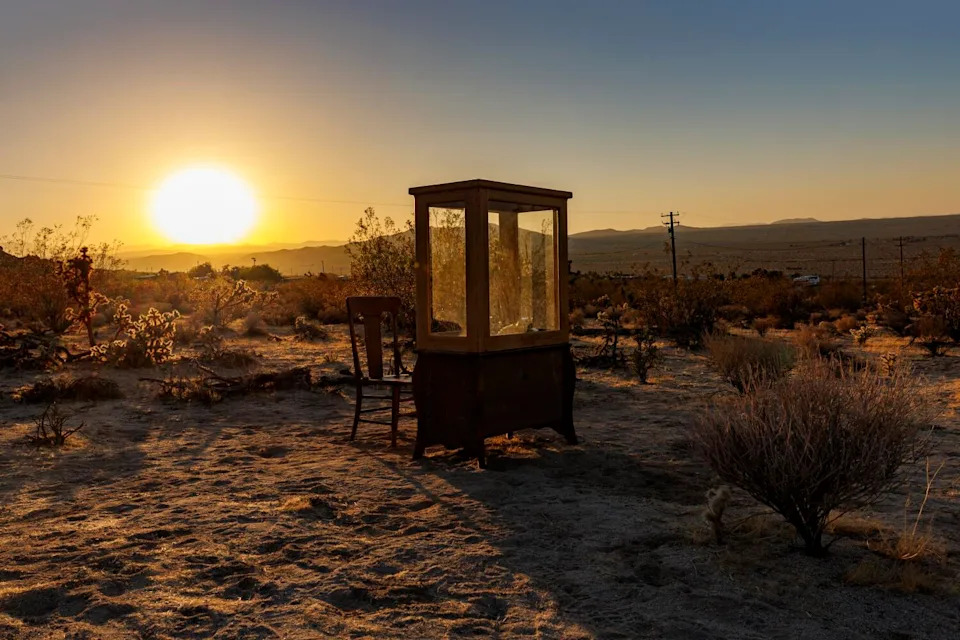 A custom phone booth in a desert setting at sunset.