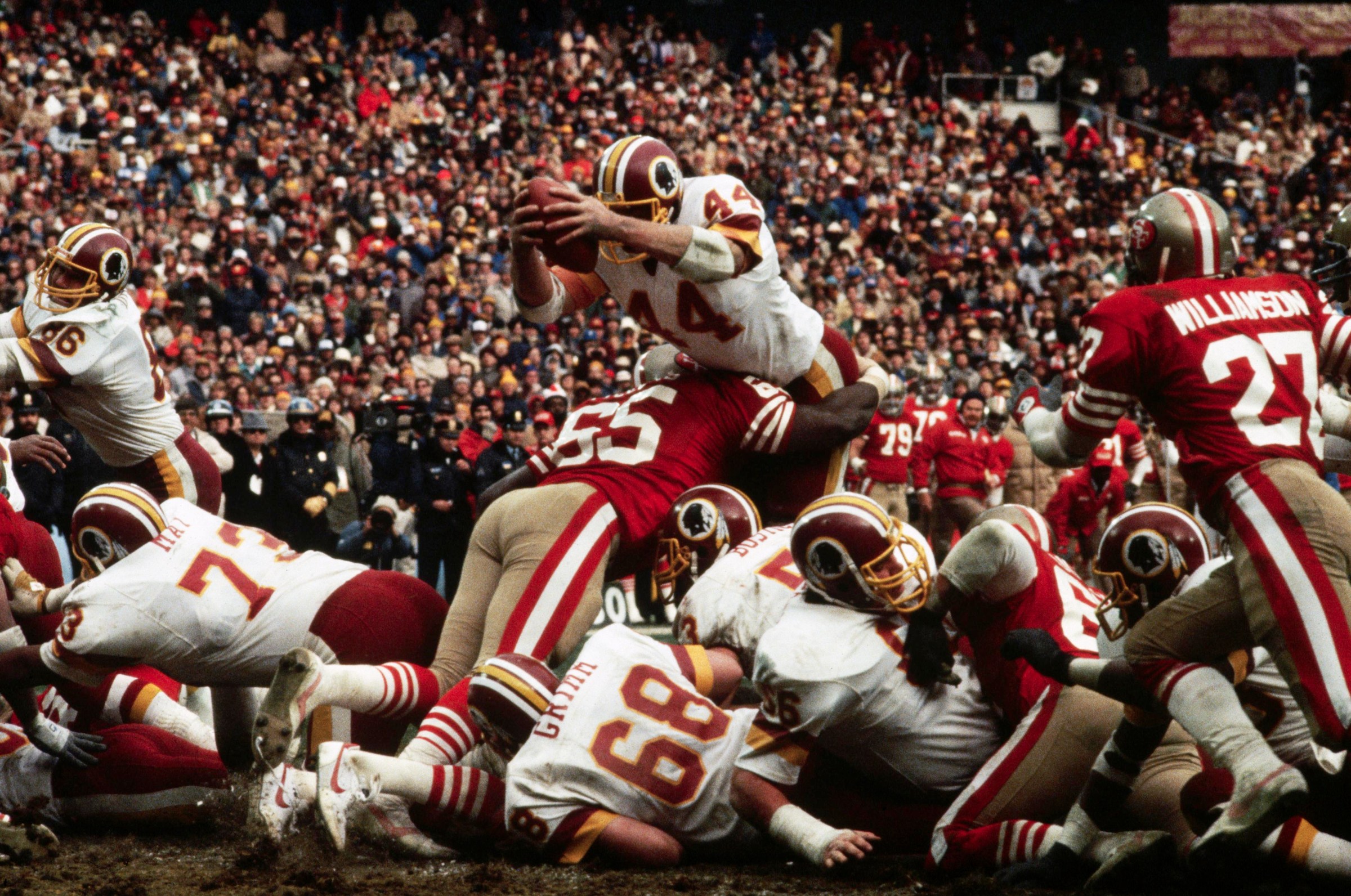 Washington Redskins running back John Riggins leaps over the defense to score a touchdown during the NFC Championship game against the San Francisco 49ers. The linebackers on the ground are May (#73), and Russ Grimm (#68). (Photo by © Wally McNamee/CORBIS/Corbis via Getty Images)