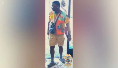 Full-body surveillance image of the suspect wearing a multicolored shirt, tan shorts and sandals in a Long Beach hit-and-run investigation.