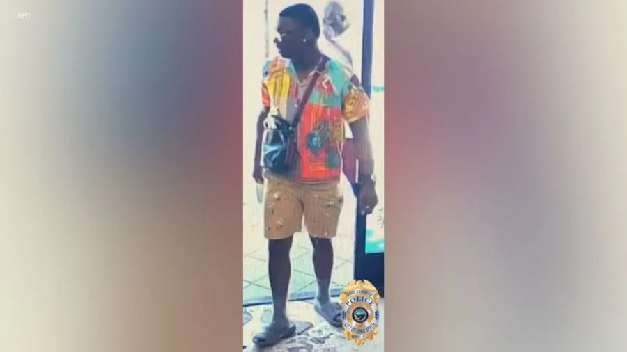 Full-body surveillance image of the suspect wearing a multicolored shirt, tan shorts and sandals in a Long Beach hit-and-run investigation.