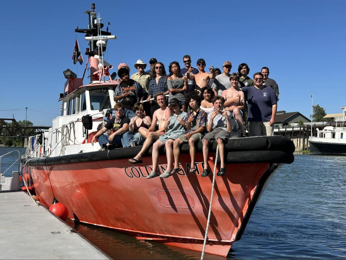 Alameda Post - A group of young people smile together on the front of a boat. They are the Sea Scouts on a large summer trip.
