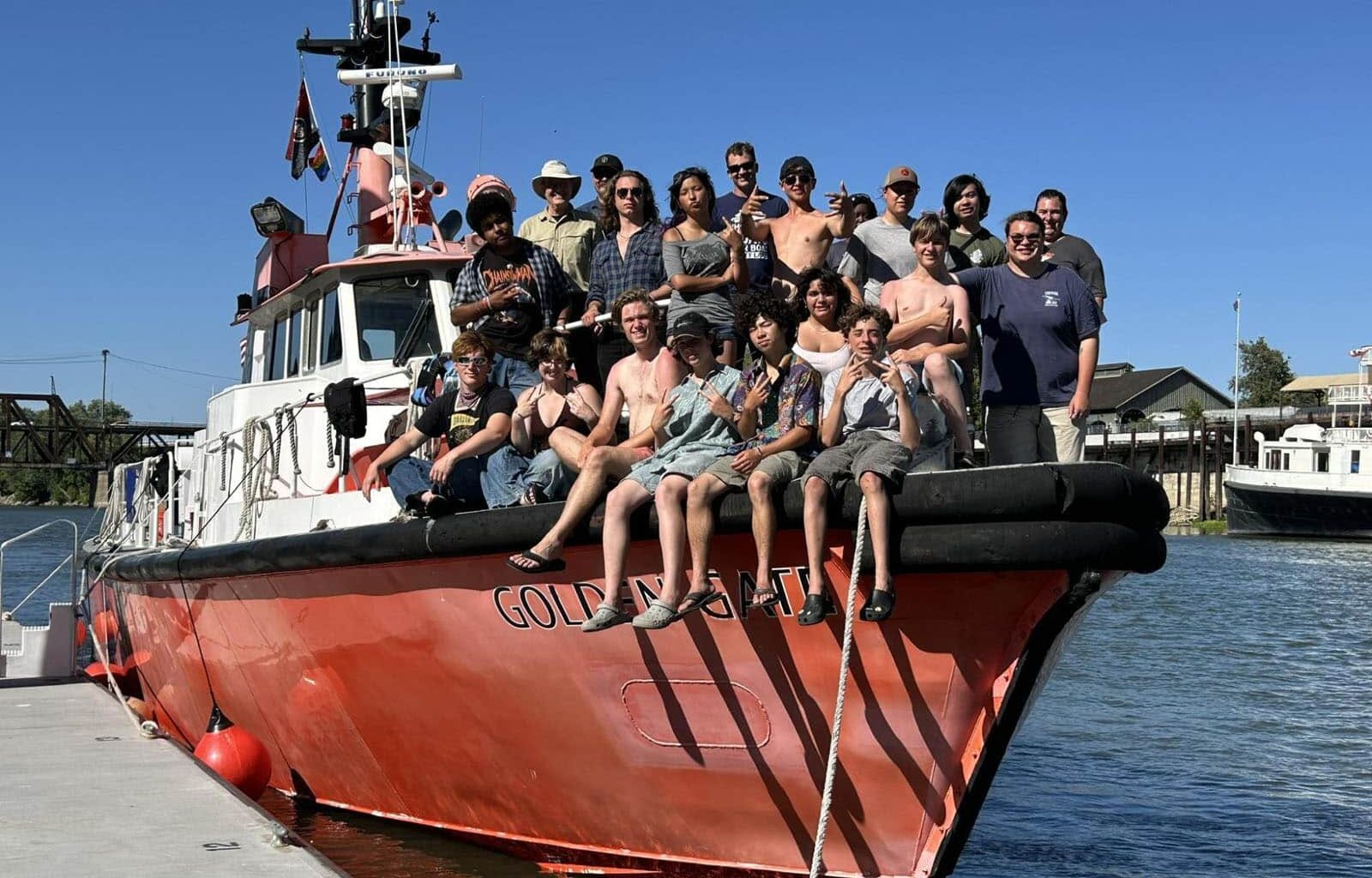 Alameda Post - A group of young people smile together on the front of a boat. They are the Sea Scouts on a large summer trip.