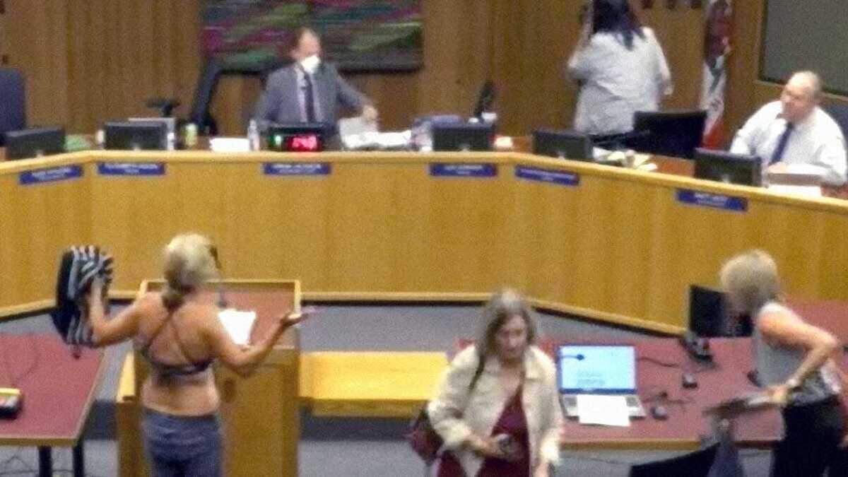 Beth Bourne removes her shirt to reveal a bathing suit while speaking at the Davis Joint Unified School District board meeting on Thursday, Sept. 18, 2025. The board twice recessed the meeting after Bourne attempted to disrobe during public comment to protest district policies on transgender students' access to locker rooms.