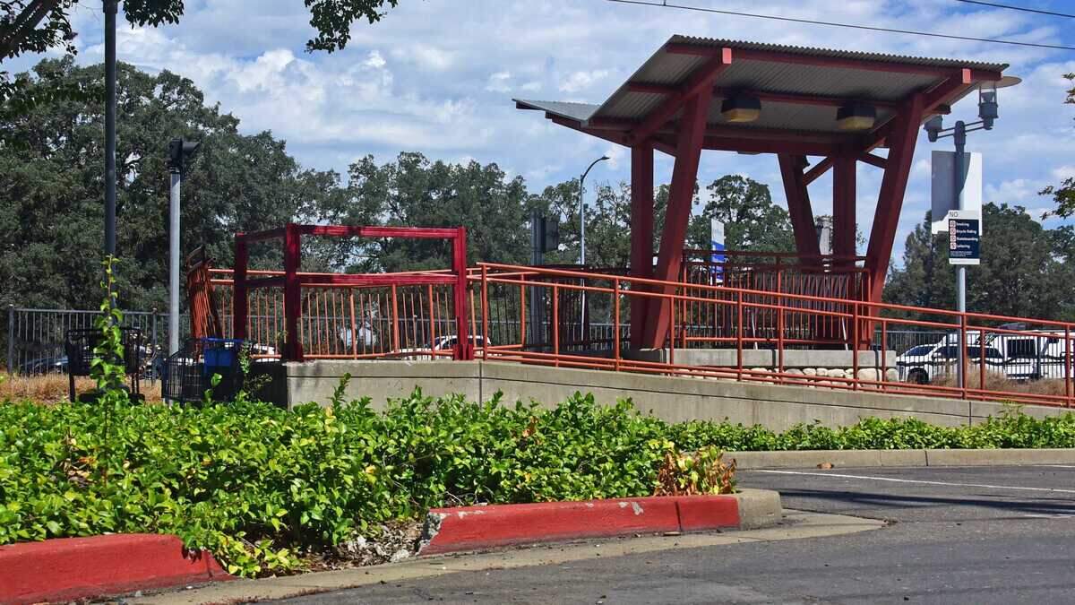 Temporary wooden railing replaces damaged metal railing and a section of curb remains missing at Iron Point Station in Folsom on Sunday, July 19, 2026, nearly six months after a car struck and killed 22-year-old dance instructor Elinor Steffy. The Sacramento County District Attorney's Office declined to file criminal charges against the driver, while Steffy's family is pursuing a civil claim alleging inadequate pedestrian protections at the station.