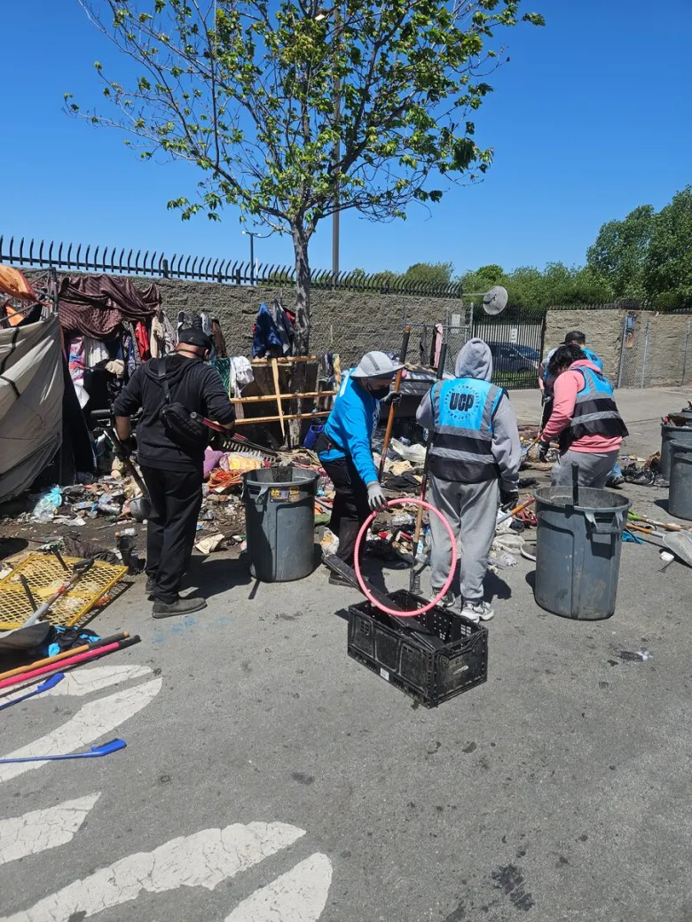 Workers pick up trash on street. 