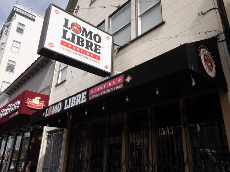 Street view of Lomo Libre Cantina, a Peruvian kitchen and bar, with its signs visible above a storefront in an urban area.