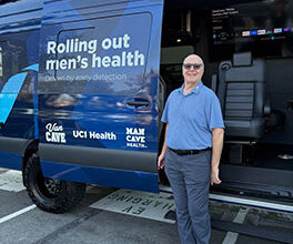 Michael Brill, wearing blue shirt and gray slacks, stands in front of the UCI Health Van Cave, a men's health screening laboratory on wheels.