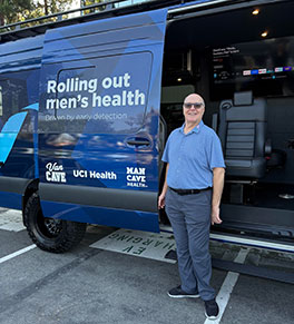 Michael Brill, wearing blue shirt and gray slacks, stands in front of the UCI Health Van Cave, a men's health screening laboratory on wheels.