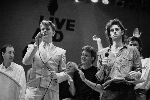 This is a Saturday, July 13, 1985 file photo of David Bowie, front left, and Bob Geldof, right, at the end of the London part of the Live Aid famine relief concert at Wembley Stadium in London. (AP Photo/Joe Schaber, File)