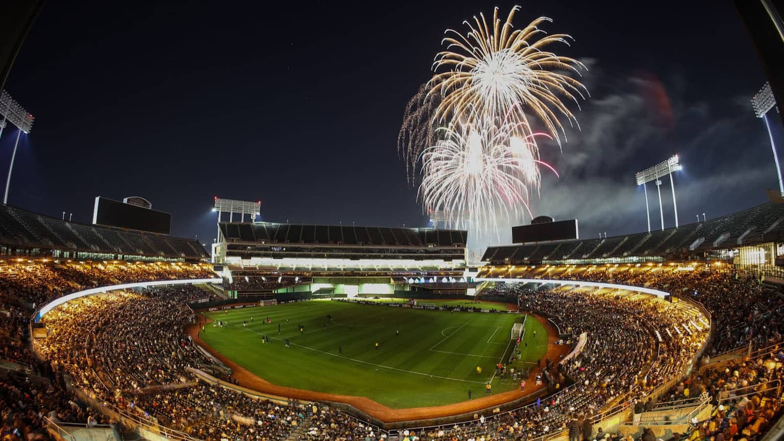 Alameda Post - The Oakland Coliseum filled with people at night, with fireworks overhead.