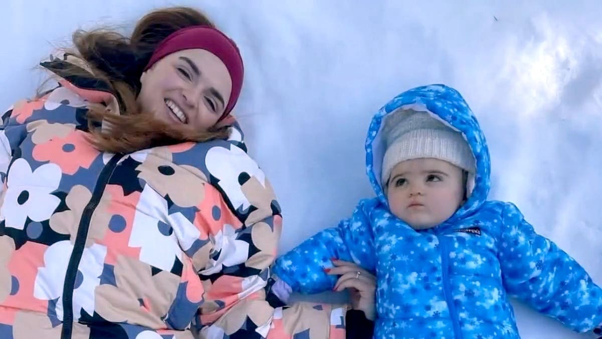 Ivana Balistreri and her young daughter, Lilliana, lie together in the snow in a family photo.