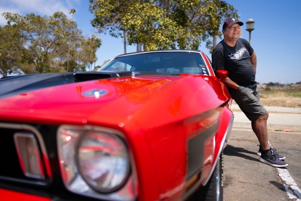 Andrew Minjares, 59, of Chula Vista, with his 1973 Ford Mustang Grande, which he has owned since he was a 17-year-old high school student in Colorado. Minjares works as a U.S. postal letter carrier for his day job and also as a DJ on Magic 92.5 in the early evening hours. As a young adult, Minjares served in the U.S. Navy. (Nelvin C. Cepeda / The San Diego Union-Tribune)