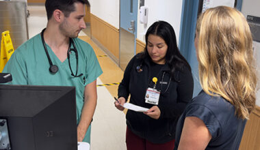 Two TEACH residents discussing a patient’s treatment plan in front of their attending physician.