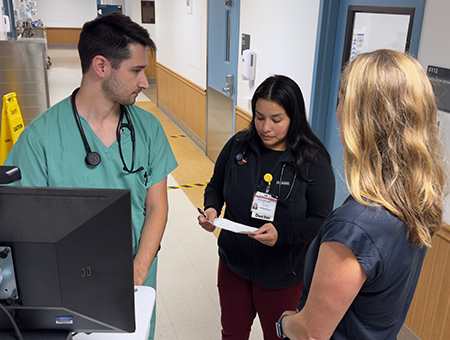 Two TEACH residents discussing a patient’s treatment plan in front of their attending physician.