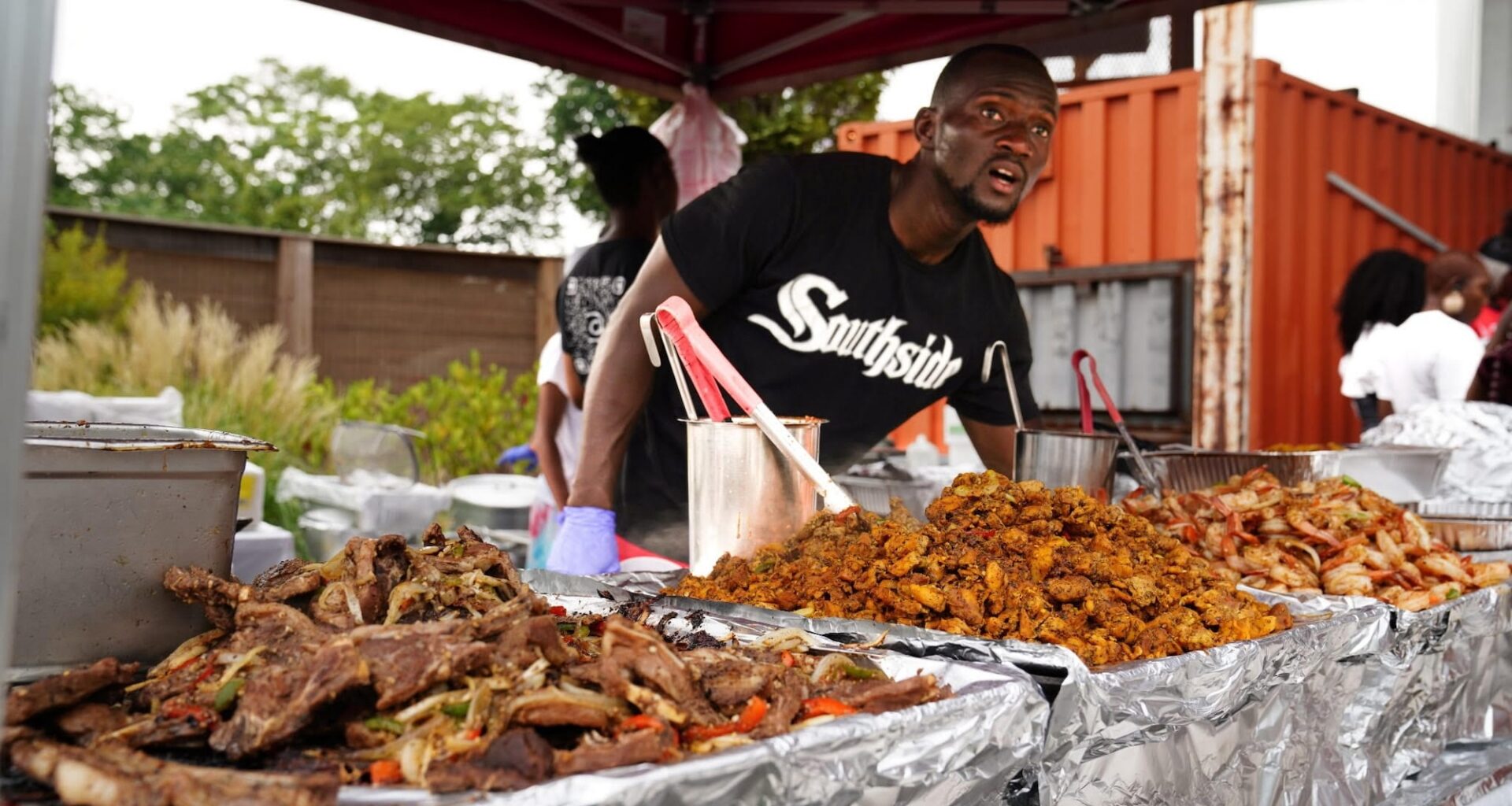 A chef standing behind large quantities of freshly cooked food.