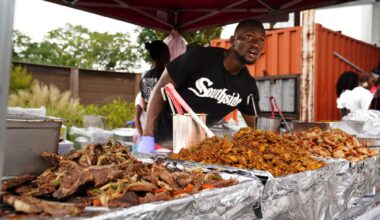 A chef standing behind large quantities of freshly cooked food.