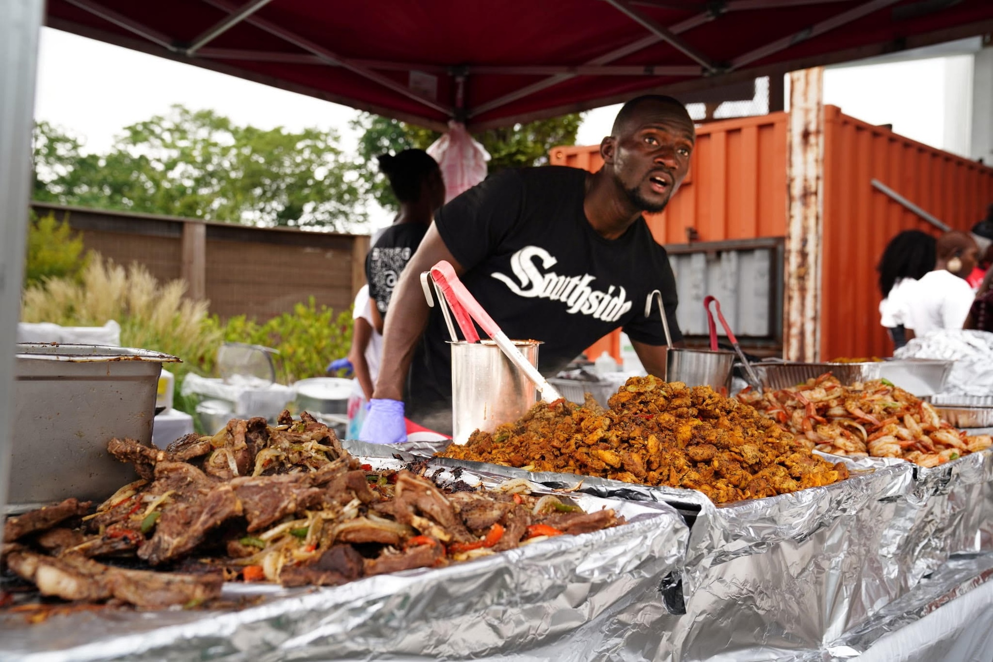 A chef standing behind large quantities of freshly cooked food.