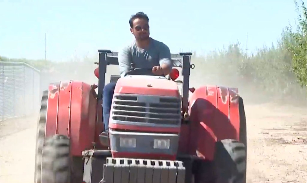 Cesar Mora driving a tractor on a dirt road.