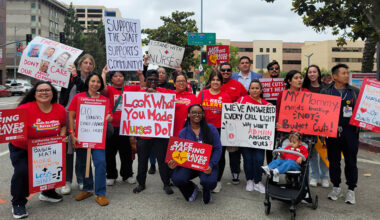 Large group of nurses outside hospital holding signs calling for patient safety and other measures