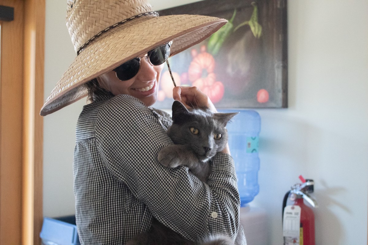 Farm and Climate Program Director Delaney Sondag holds the farm’s resident mouser “Gray Kitty” Thursday, July 30, 2026, in Woodland. Sondag says his name is legally Buddy, but no one calls him that.