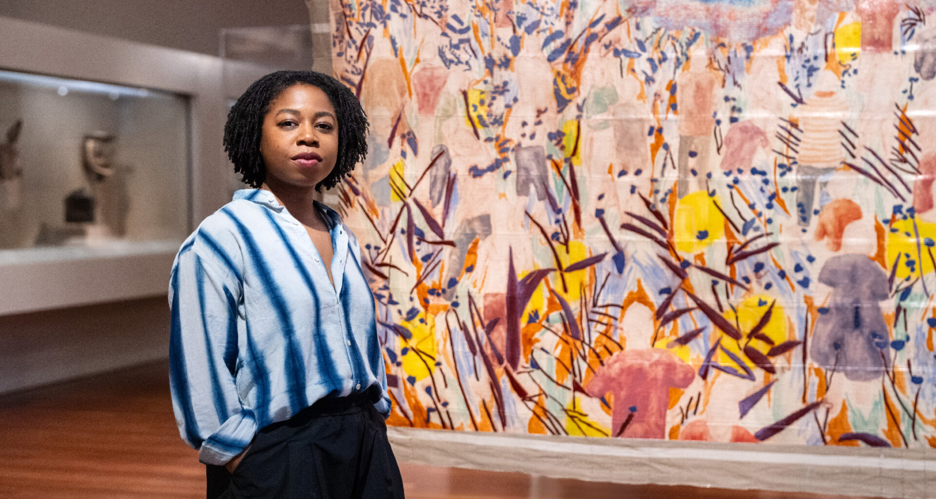 young Black woman stands in front of painting in museum gallery
