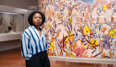 young Black woman stands in front of painting in museum gallery