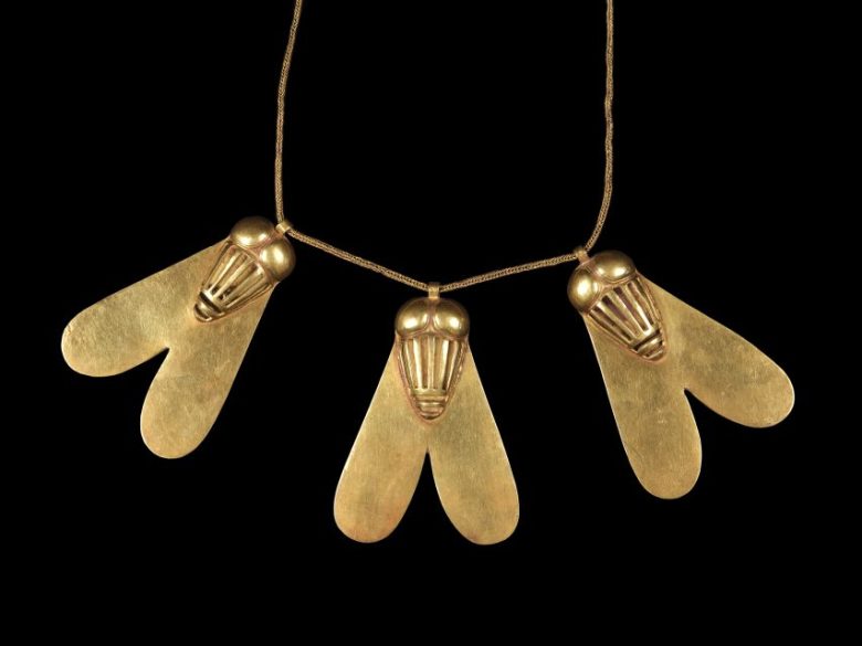 Gold necklace featuring three bee or insect-shaped pendants with heart-like wings, strung on a fine chain, against a black background.