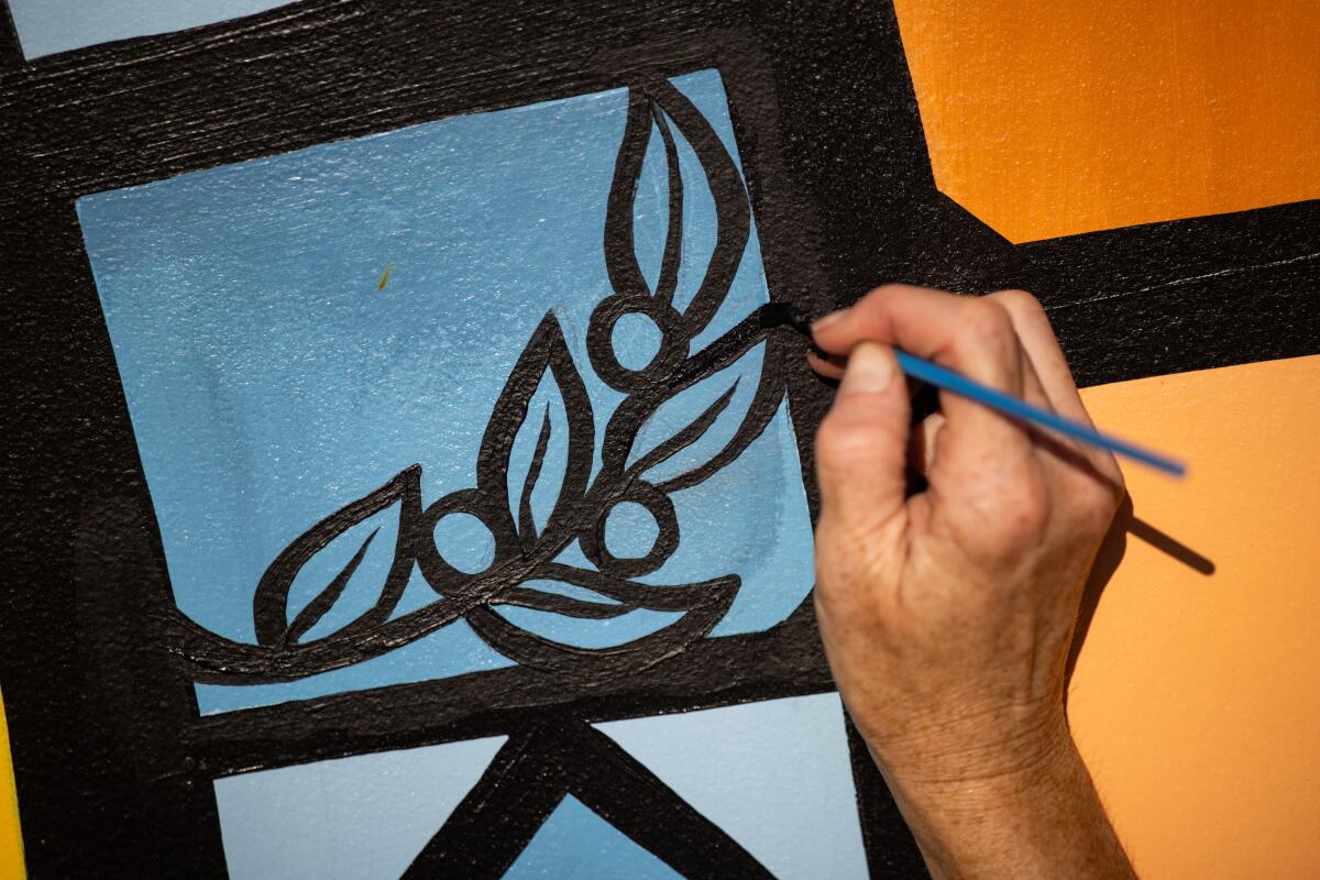 Miriam Hellmann paints an olive branch on the mural outside the Pasadena Jewish Temple & Center.