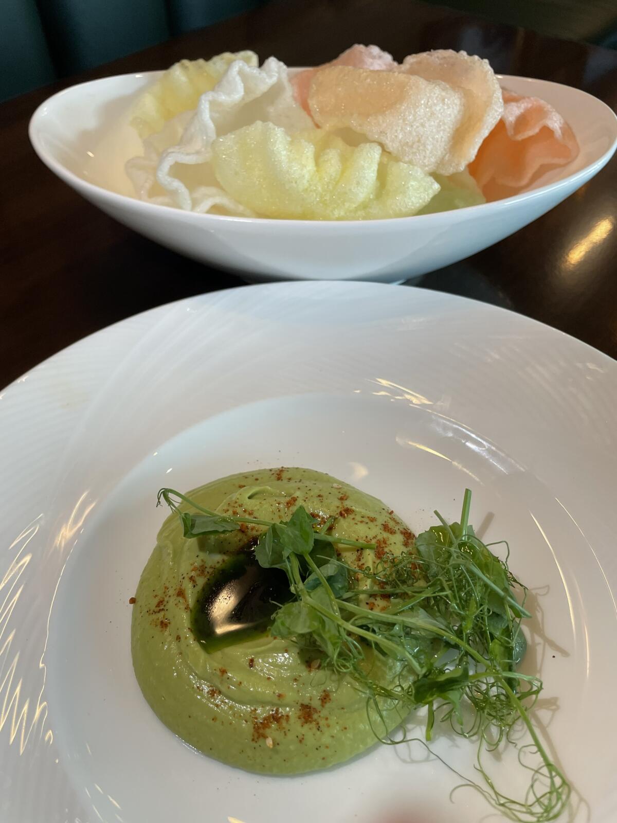 Pea guacamole, comprised of peas and avocados blended together to make a smooth purée, is served with shrimp chips.