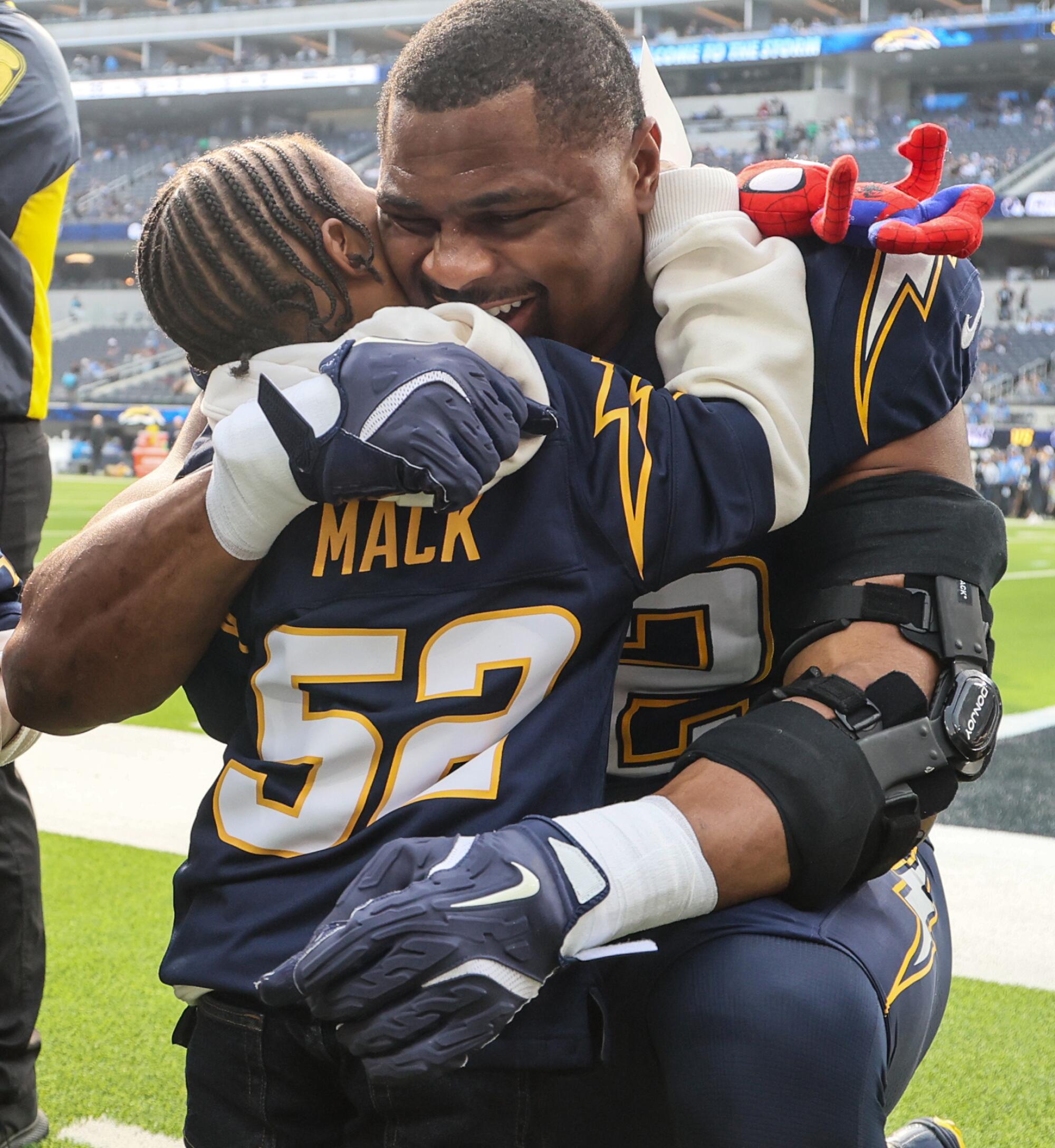 Chargers linebacker Khalil Mack embraces one of his son on the sideline before a game against the Raiders at SoFi Stadium.