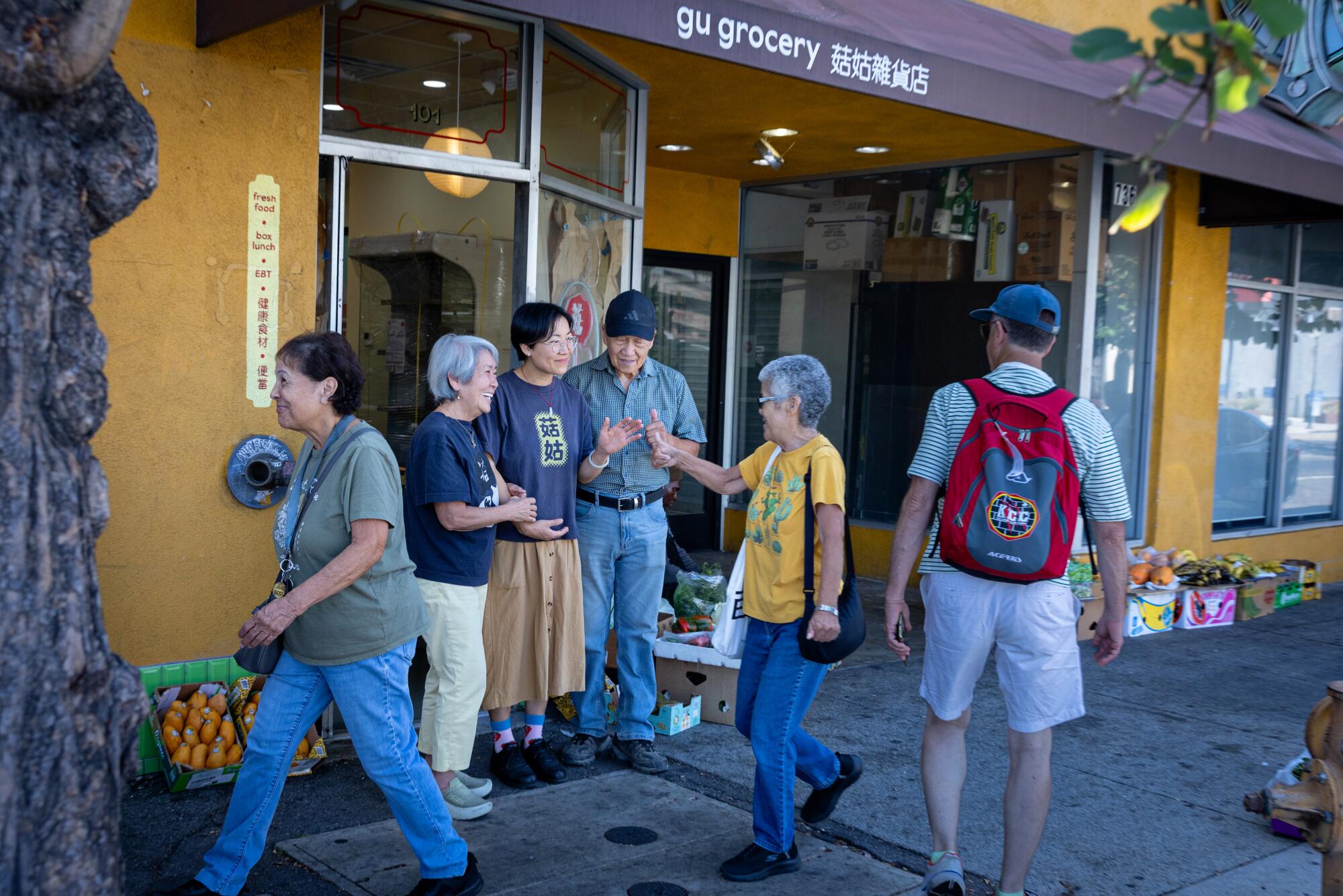 Jessica Wang and her parents Peggy and Willie Wang greet Chinatown residents outside of their storefront Gu Grocery.