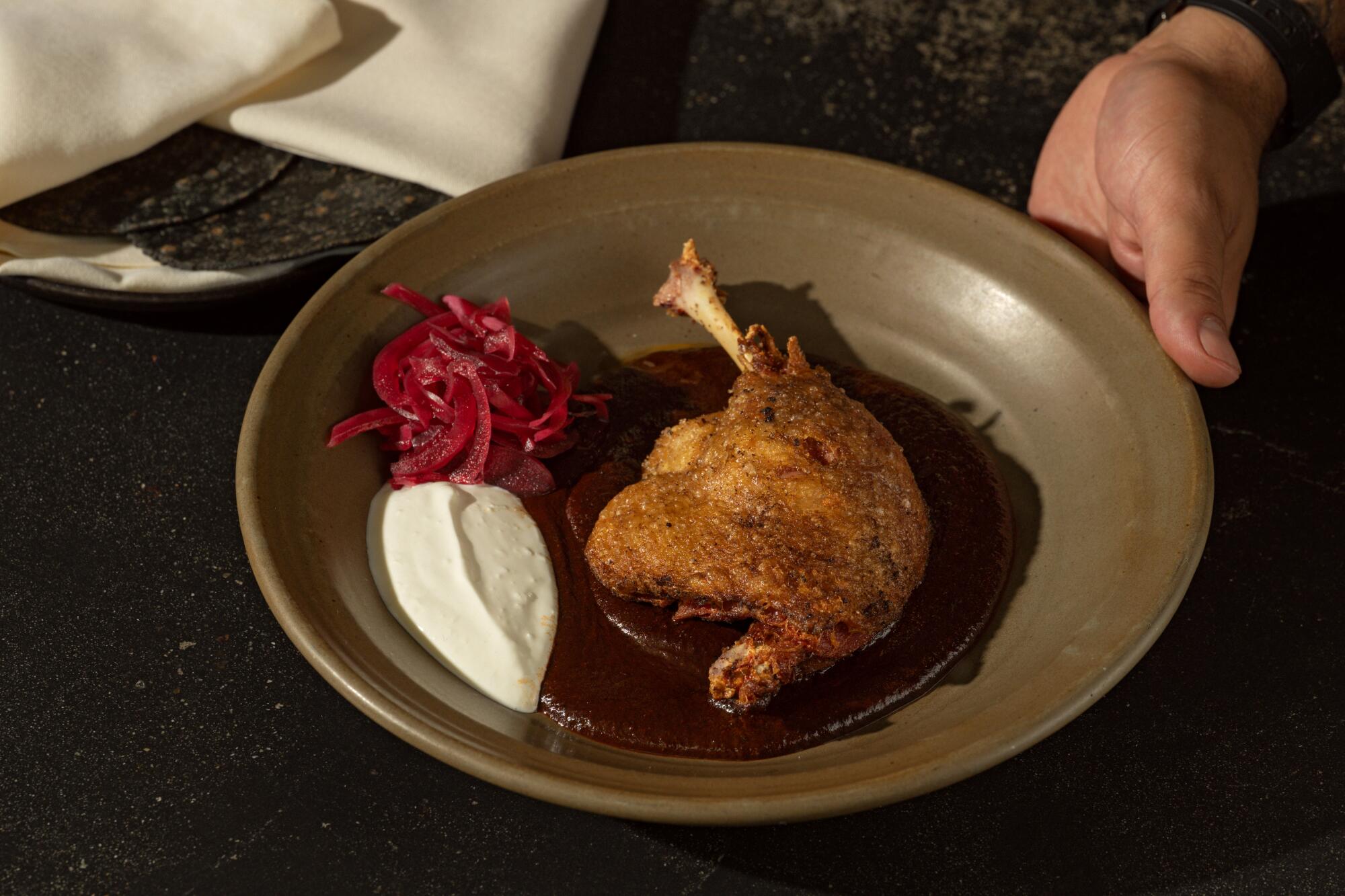 A mole made with dates served underneath a duck leg confit at A Tí.
