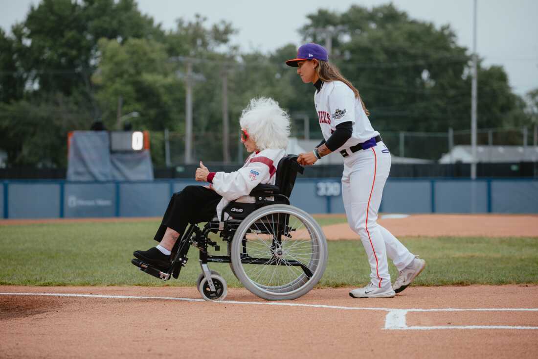 Kelsie Whitmore (right), no. 1 draft pick of the San Francisco Firebells and of the WPBL overall draft, guides veteran baseball player Maybelle Blair, 99, off the field after the first pitch ceremony on Opening Day of the WPBL. Springfield, IL, August 1, 2026.