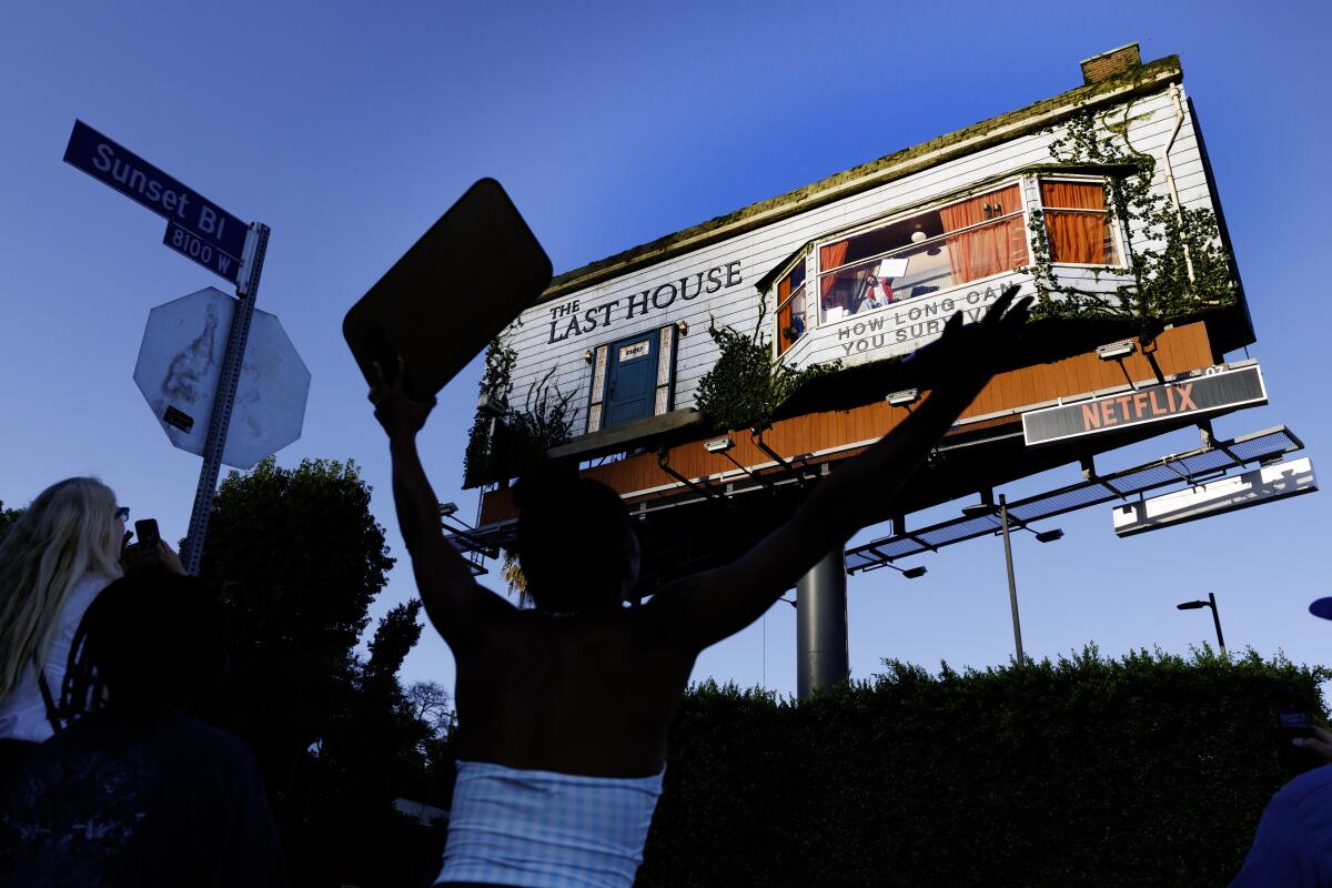 A passerby gestures to the man living in a billboard