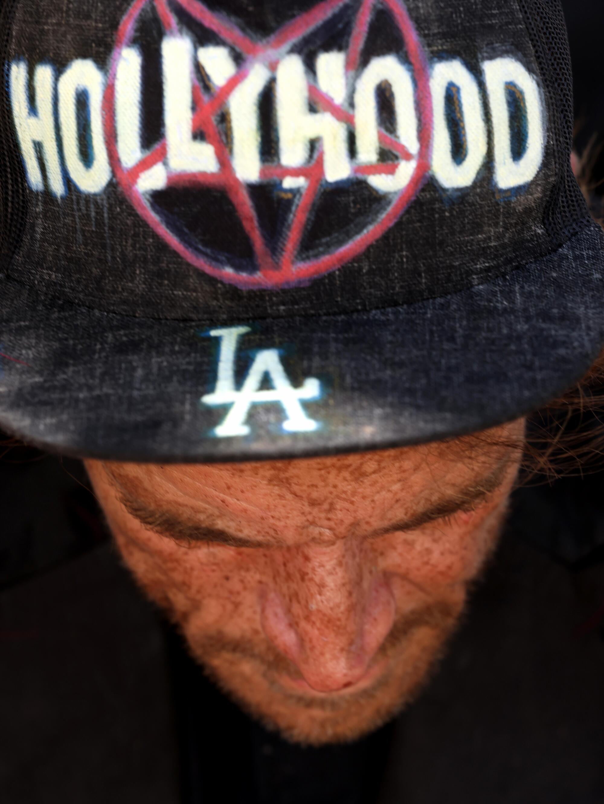 A homeless man wears a hat that reads Hollywood and L.A.