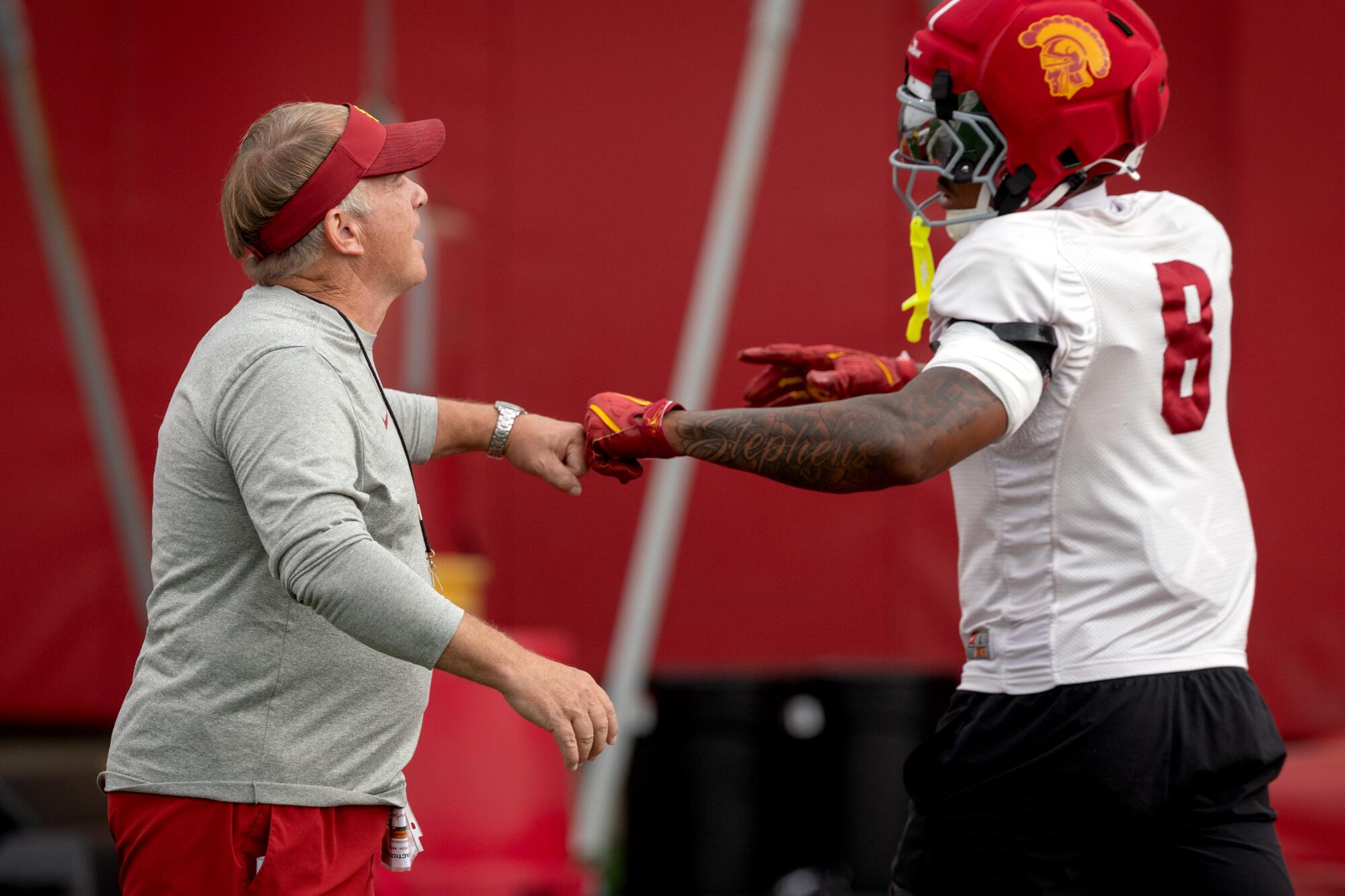 USC defensive coordinator Gary Patterson fist bumps linebacker Desman Stephens during practice on Aug. 5.