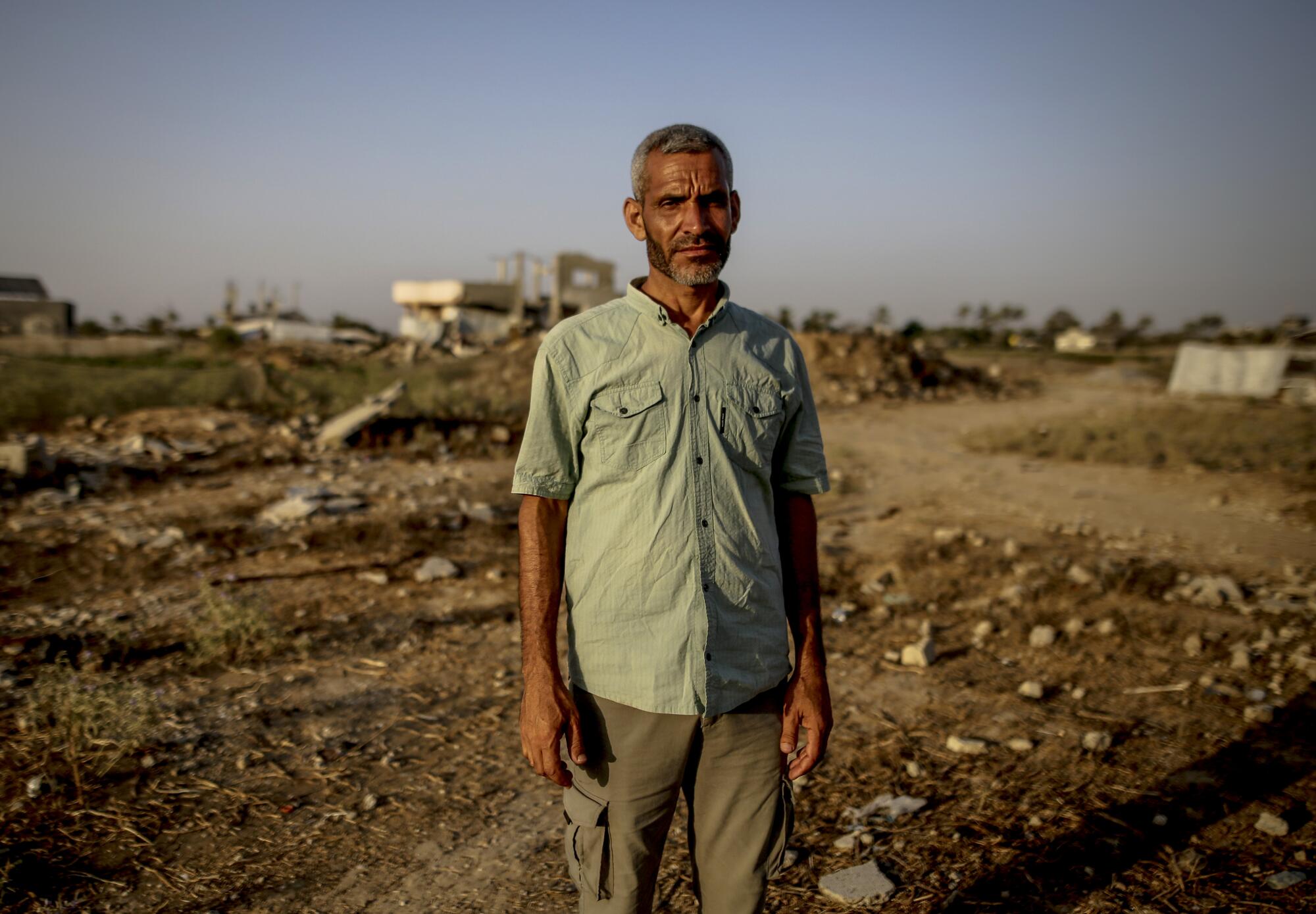 a man stands in a dirt field at sunset for a portrait