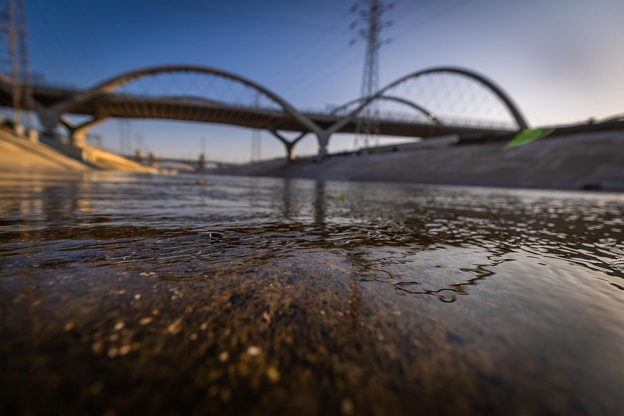 The Los Angeles River runs under the Sixth Street Bridge at sunset
