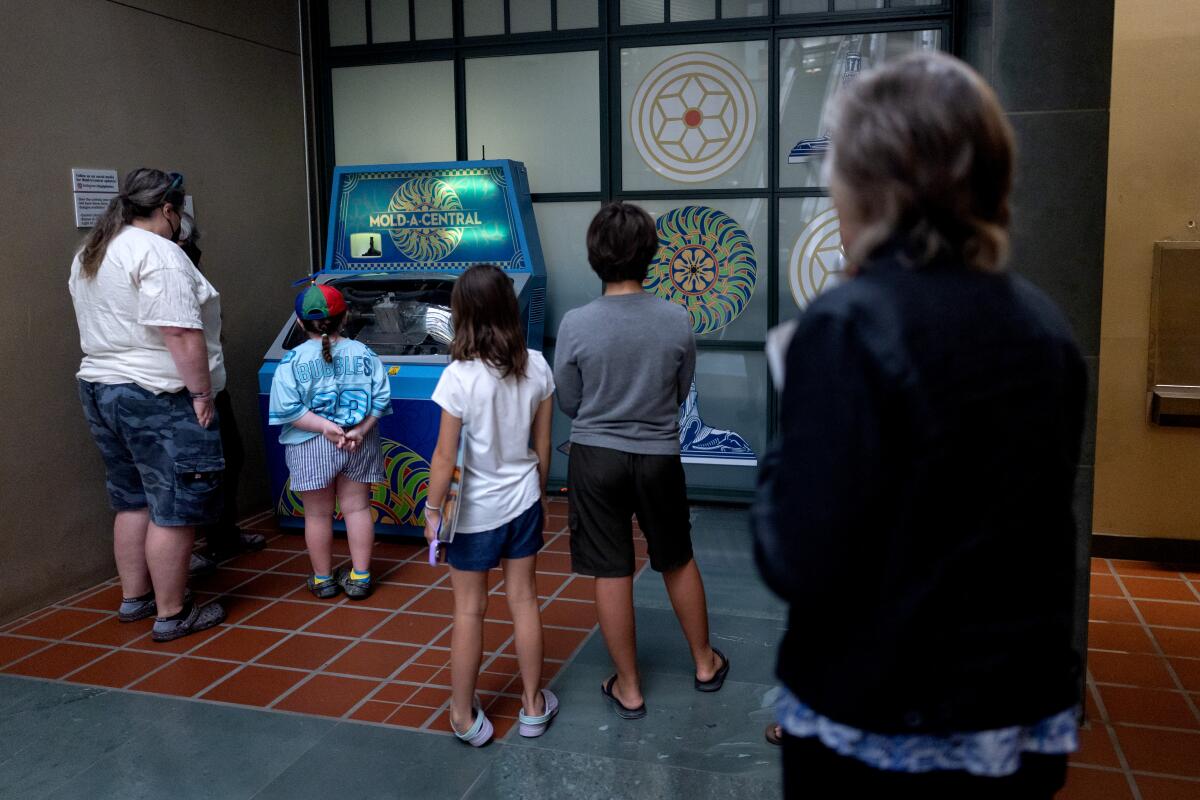 People line up to use the bright blue and turquoise vending machine that makes sphinxes.