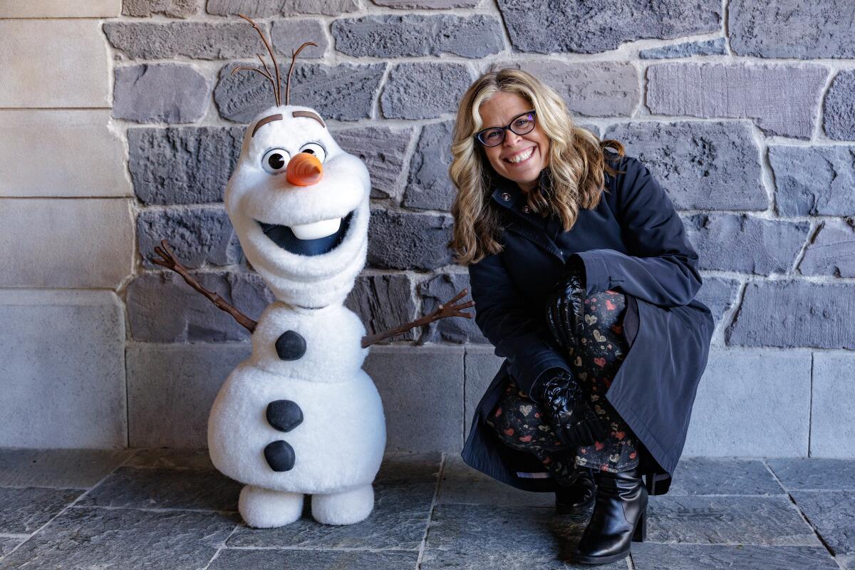 A robotic snowman (Olaf) with a woman in glasses. 